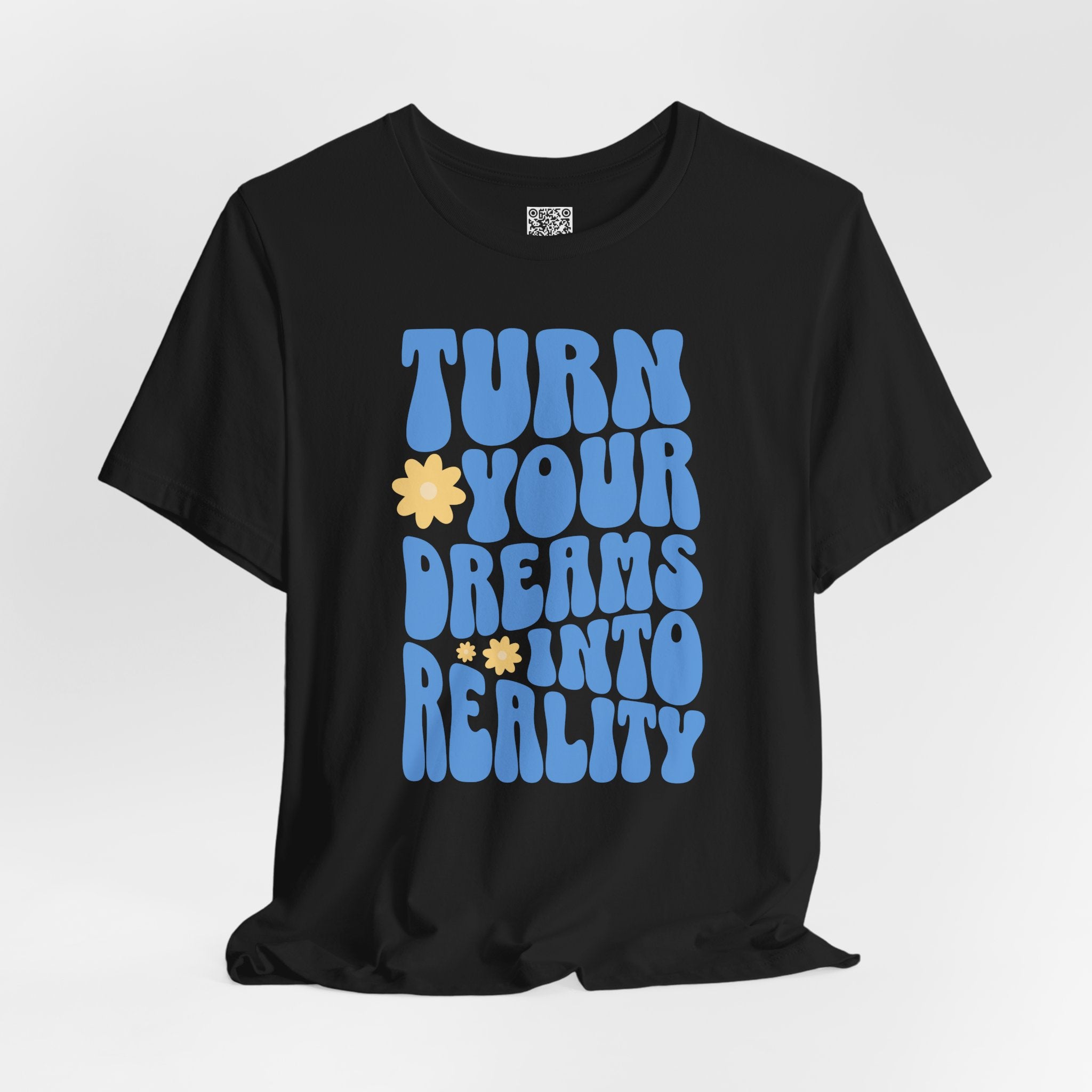 Black t-shirt with blue retro wavy text "TURN YOUR DREAMS INTO REALITY" and yellow flower accents.