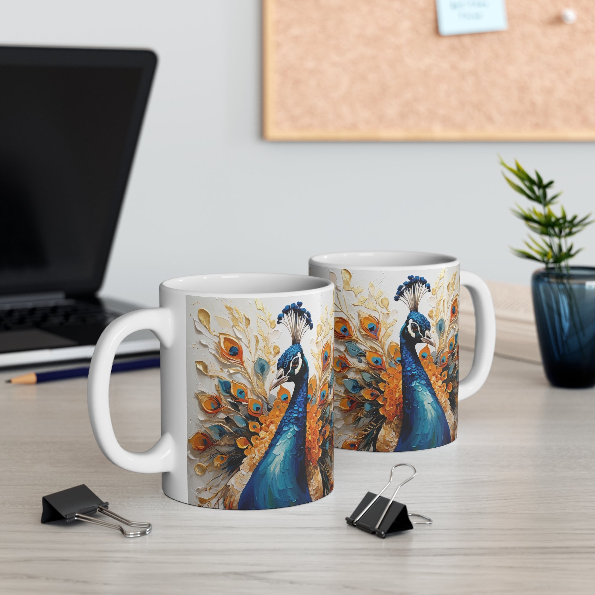 Two mugs with peacock designs on a desk with office supplies.