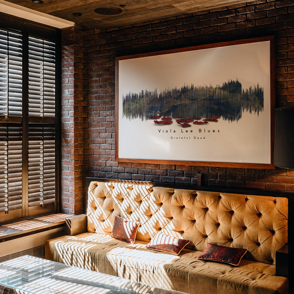 Cozy living room with a brown leather sofa, brick wall, and framed artwork.
