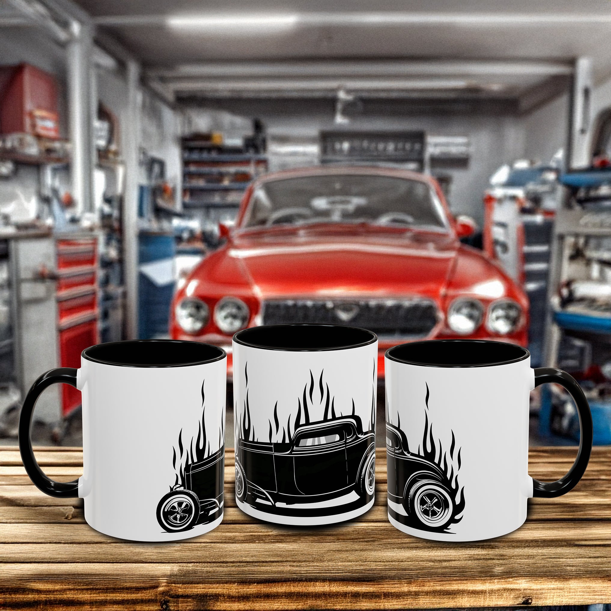 Three mugs with Hot Rod car design on a wooden surface in a garage setting with a red car in the background.