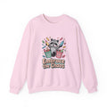 Pink sweatshirt with a raccoon graphic and 'Embrace the Chaos' text on a white background