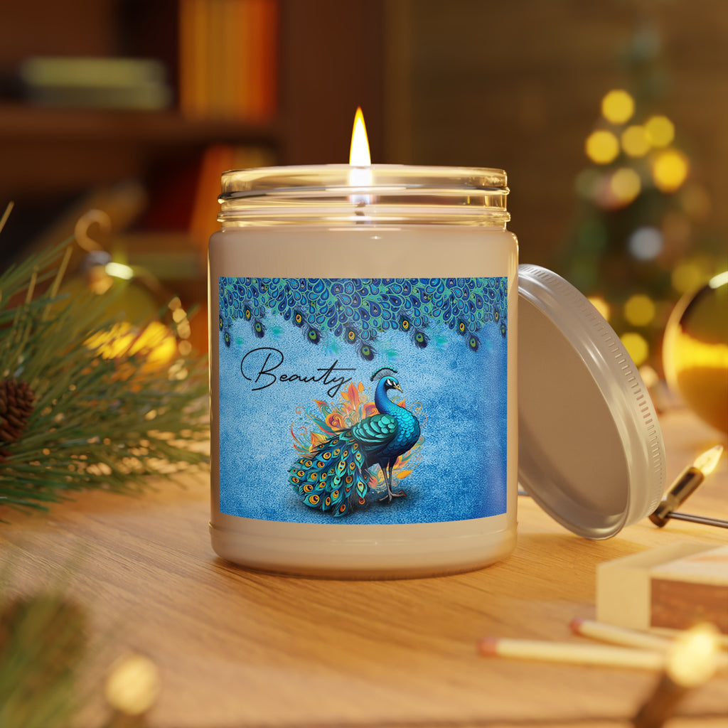 Candle in a jar with a peacock design and 'Beauty' text, set against a warm, blurred indoor background.