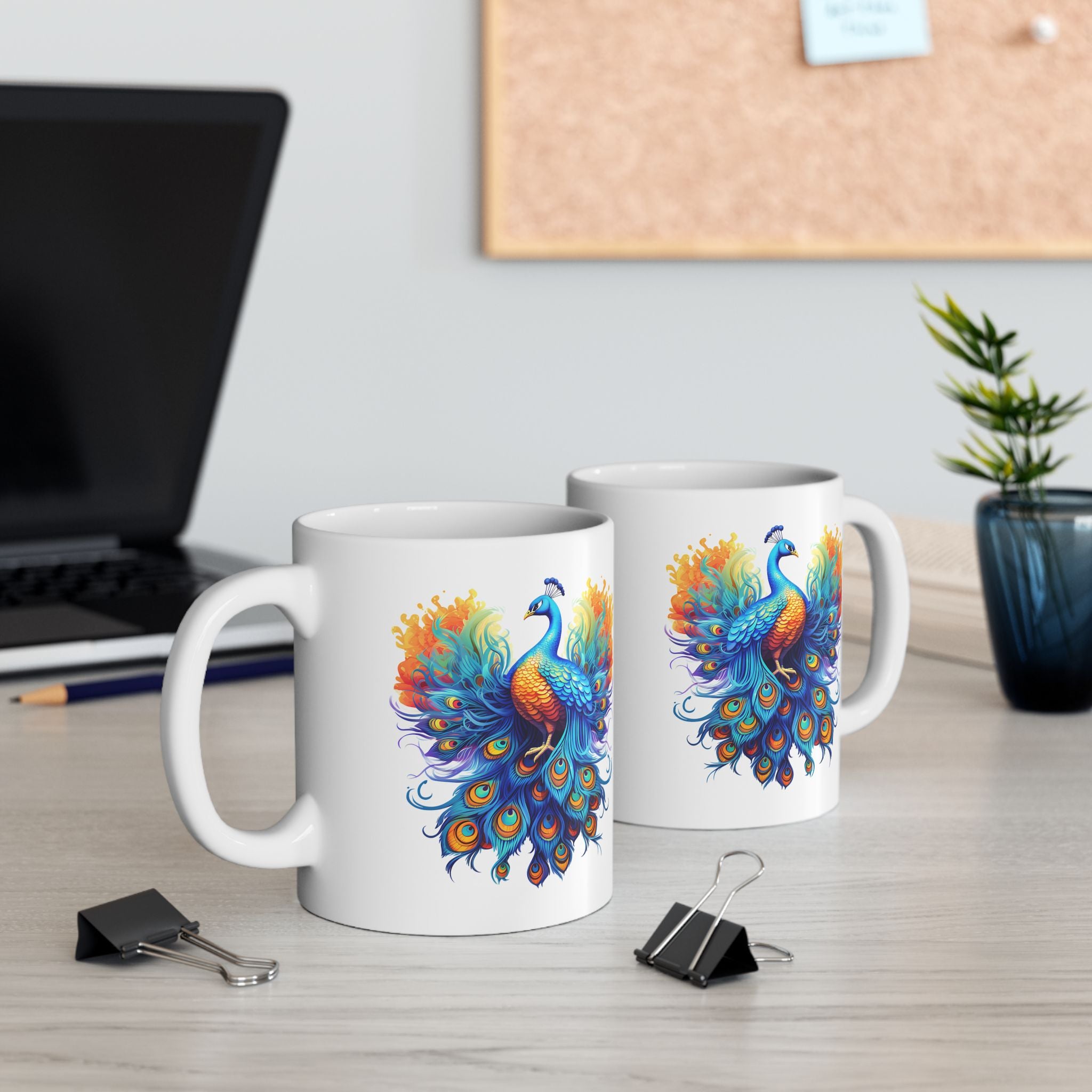 Two mugs with peacock designs on a desk with office supplies.