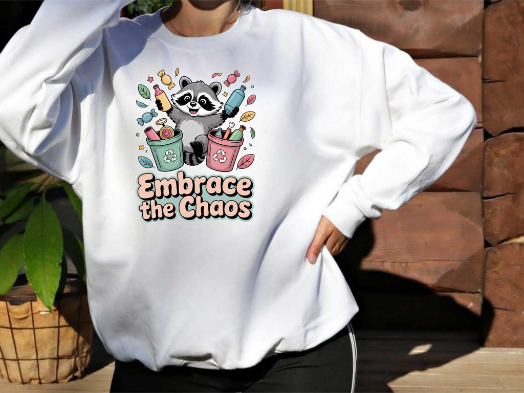 Person wearing a white sweatshirt with a graphic design and text 'Embrace the Chaos' outdoors.