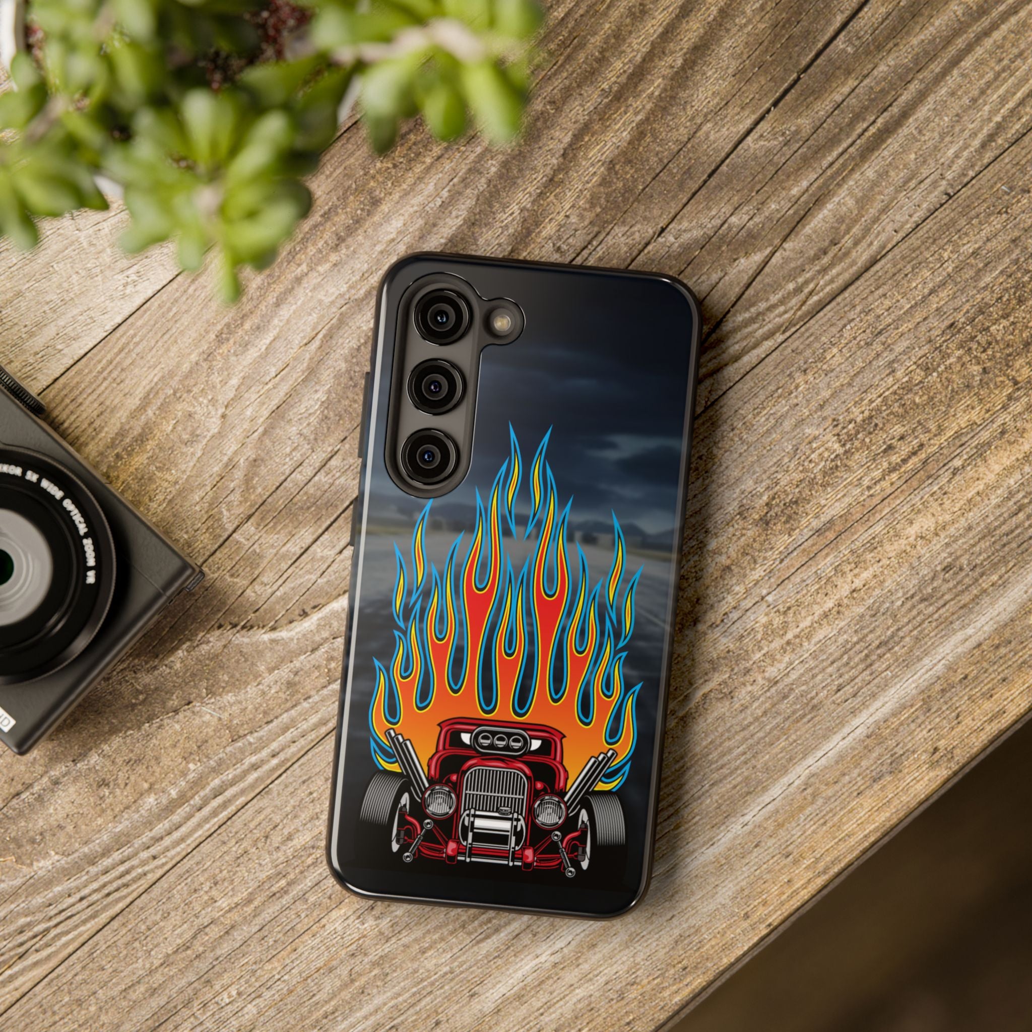 Phone case with a hot rod and flame design on a wooden surface