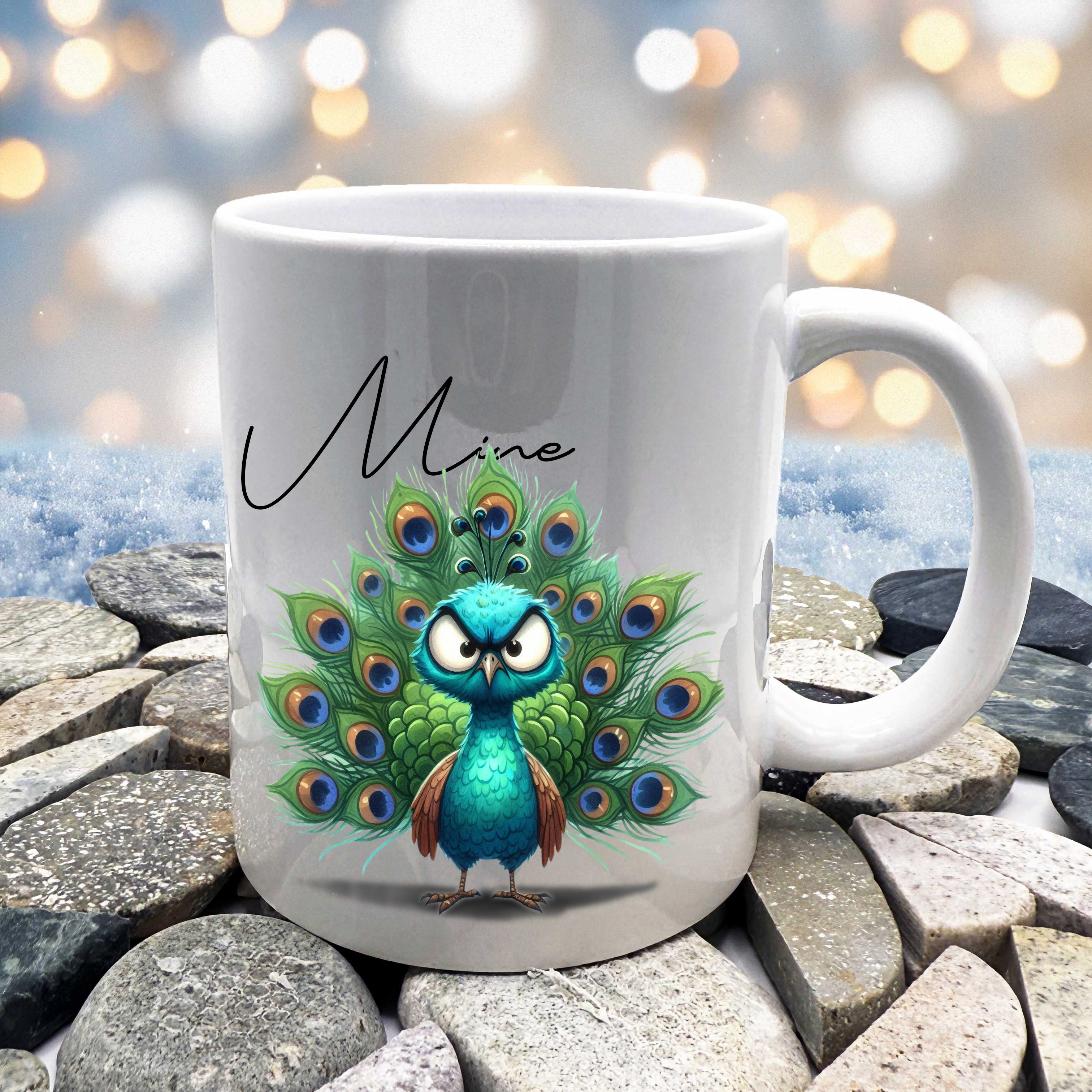 White mug with a peacock design and 'Mine' text, placed on stones with a blurred light background