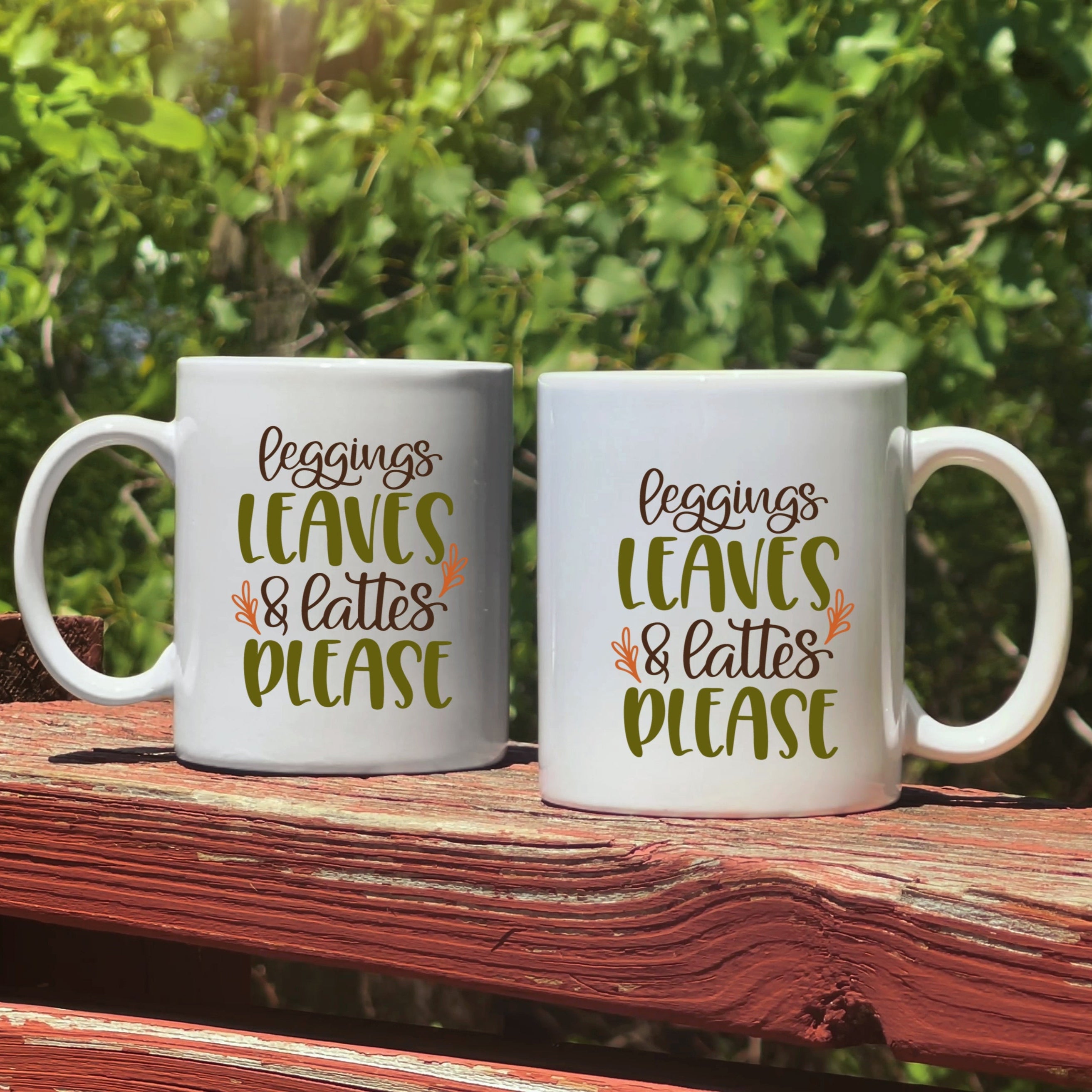 Two mugs with humorous text on a wooden surface outdoors