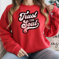 Woman in red "Trust Your Soul" sweatshirt, cozy crewneck pullover, inspirational casual wear, for everyday comfort