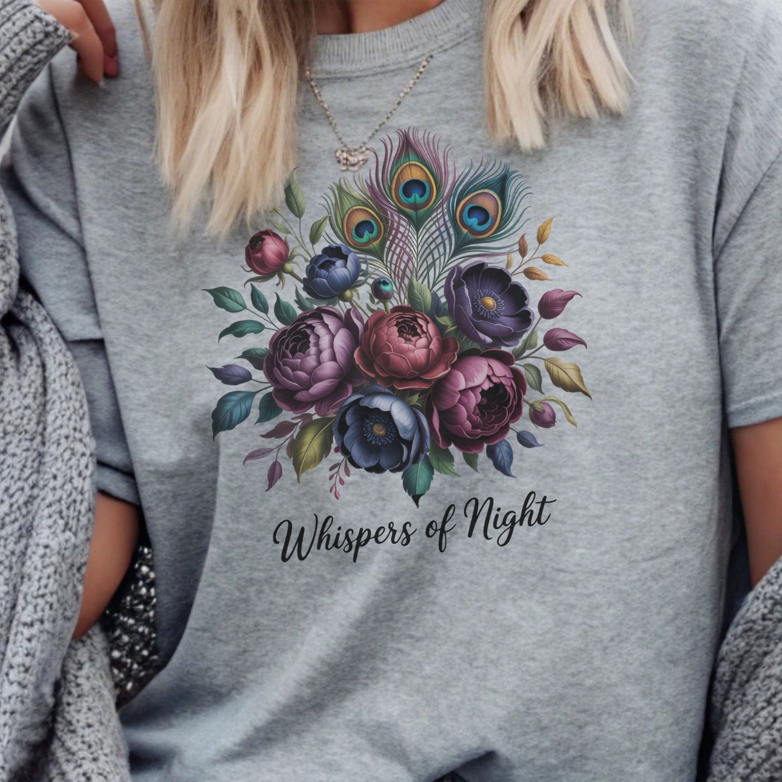 Gray t-shirt with a floral design and text 'Whispers of Night' worn by a person.
