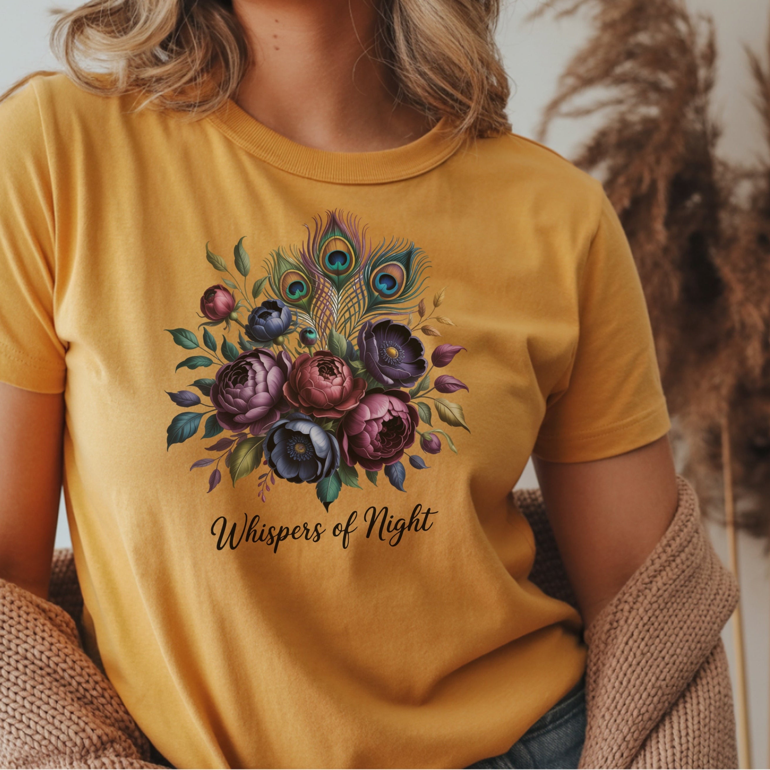 Person wearing a yellow t-shirt with a floral design and text, sitting against a neutral background.