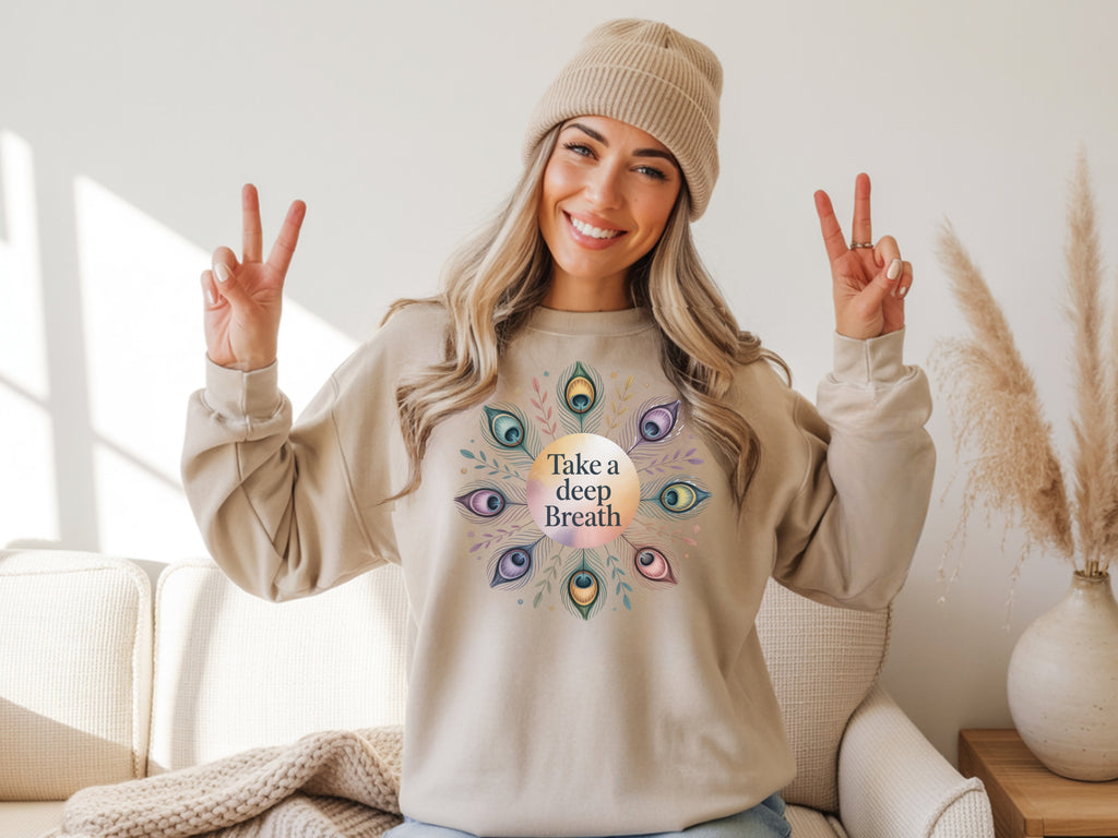 Person wearing a beige sweatshirt with a 'Take a Deep Breath' design, making peace signs.
