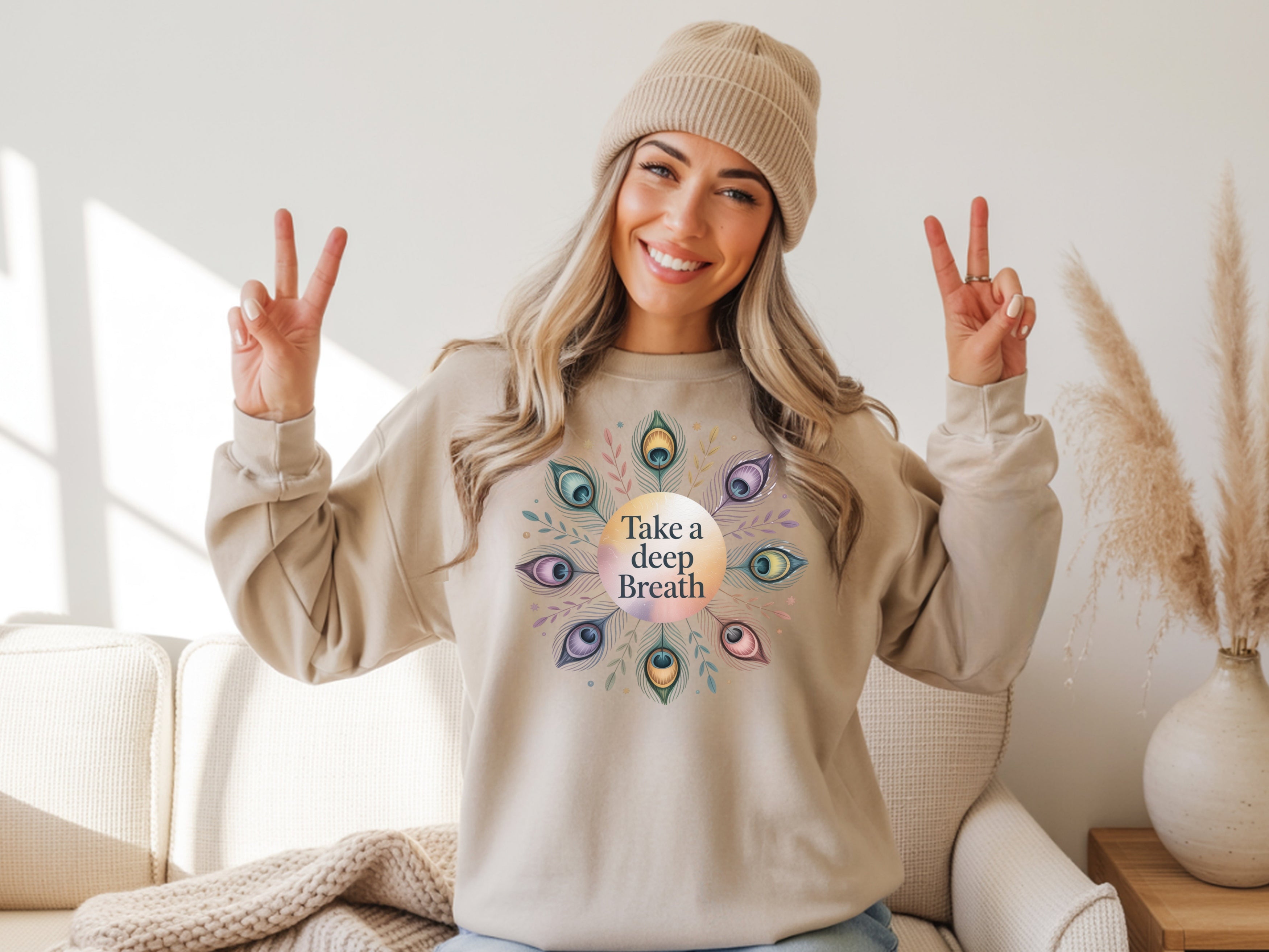 Person wearing a beige sweatshirt with a 'Take a Deep Breath' design, making peace signs.