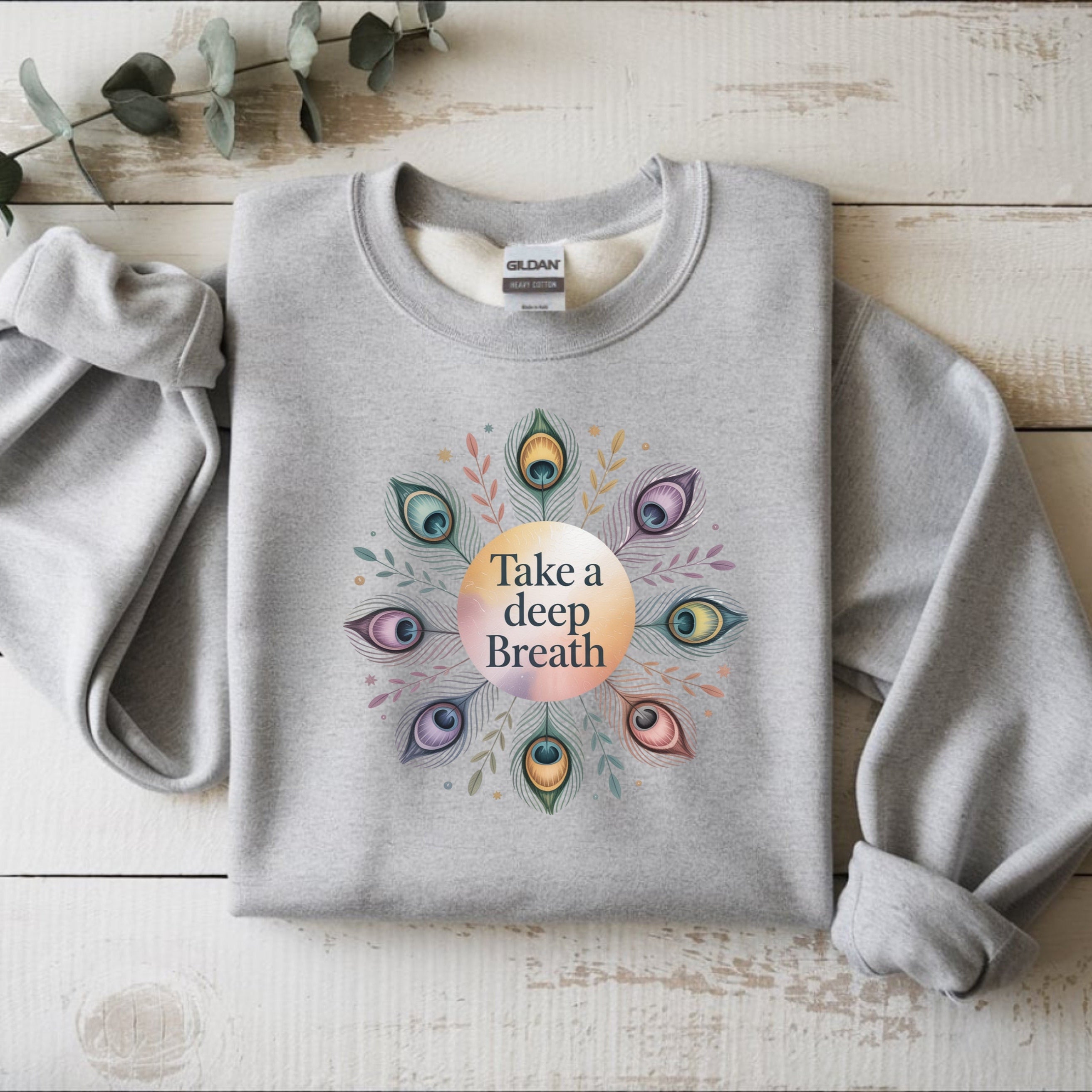 Gray sweatshirt with a colorful design and 'Take a deep Breath' text on a wooden surface.