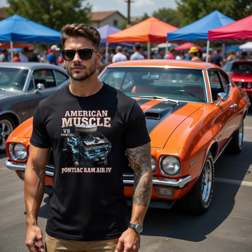 Man wearing a black t-shirt with 'American Muscle' design in front of an orange Pontiac Ram Air IV muscle car at a car show.