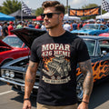 Man wearing a Mopar 426 Hemi t-shirt at a car show with classic cars in the background.