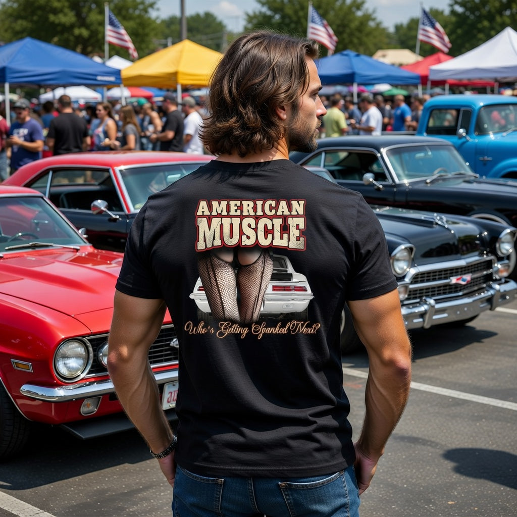 Man wearing a 'American Muscle' Chevy Camaro t-shirt at a car show with vintage cars in the background.